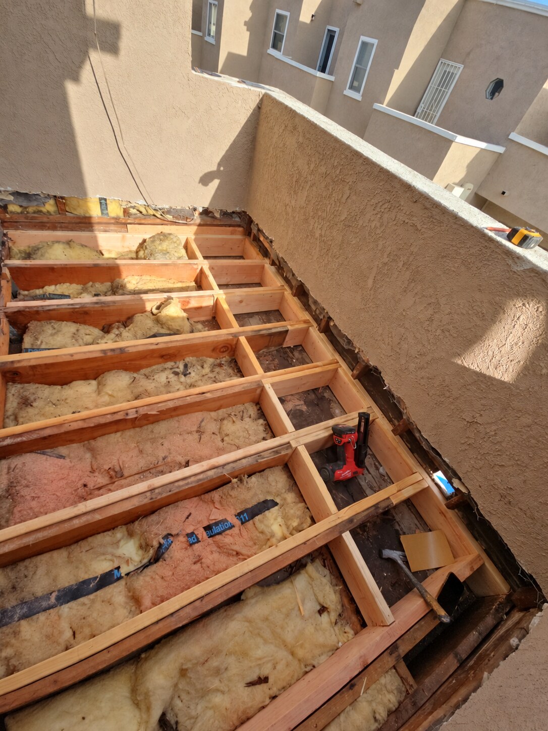 Before waterproofing: existing balcony deck opened for reframing with exposed joists and insulation
