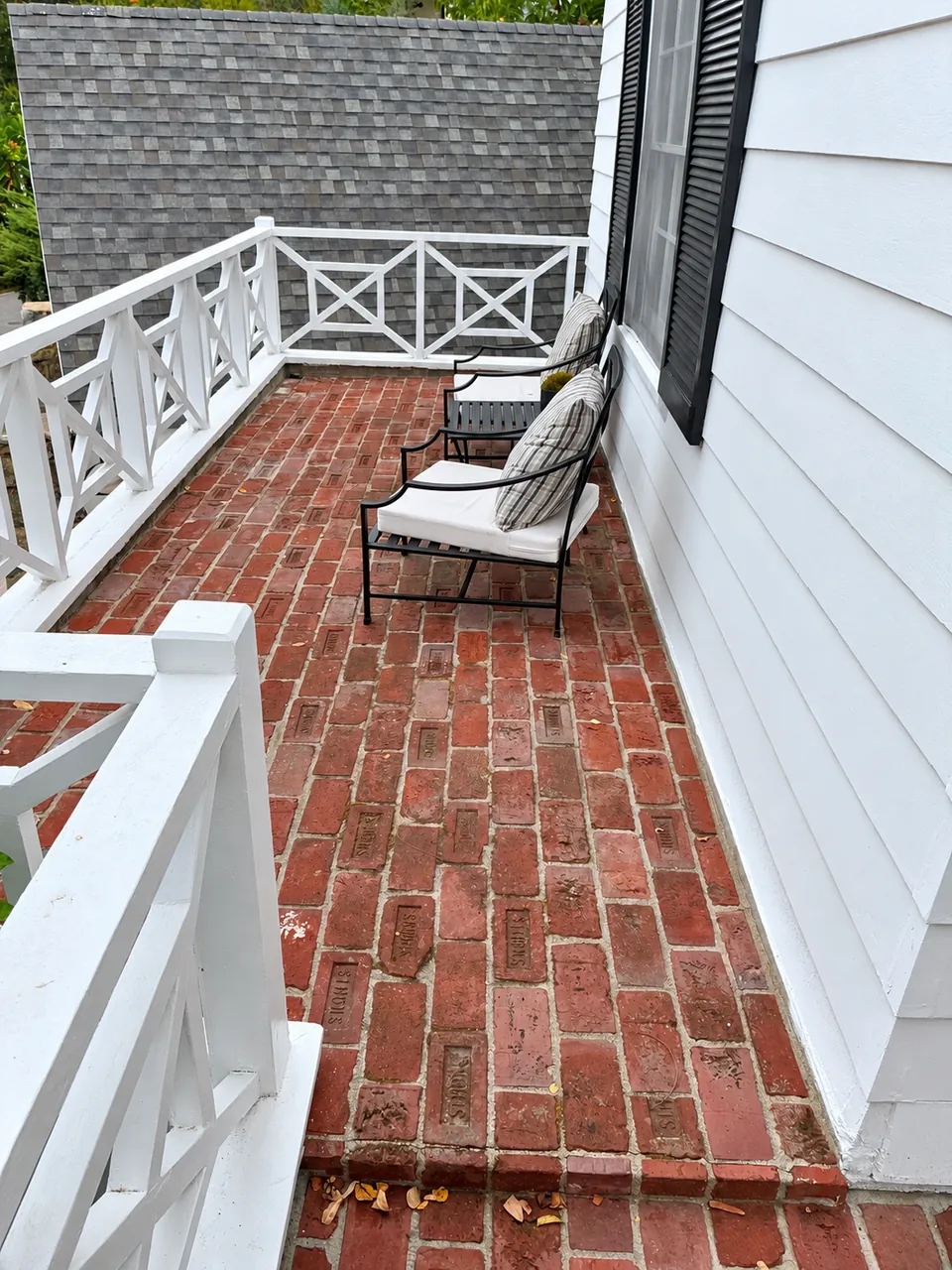 Before waterproofing: existing red tile balcony in Beverly Hills with white railings and patio chairs