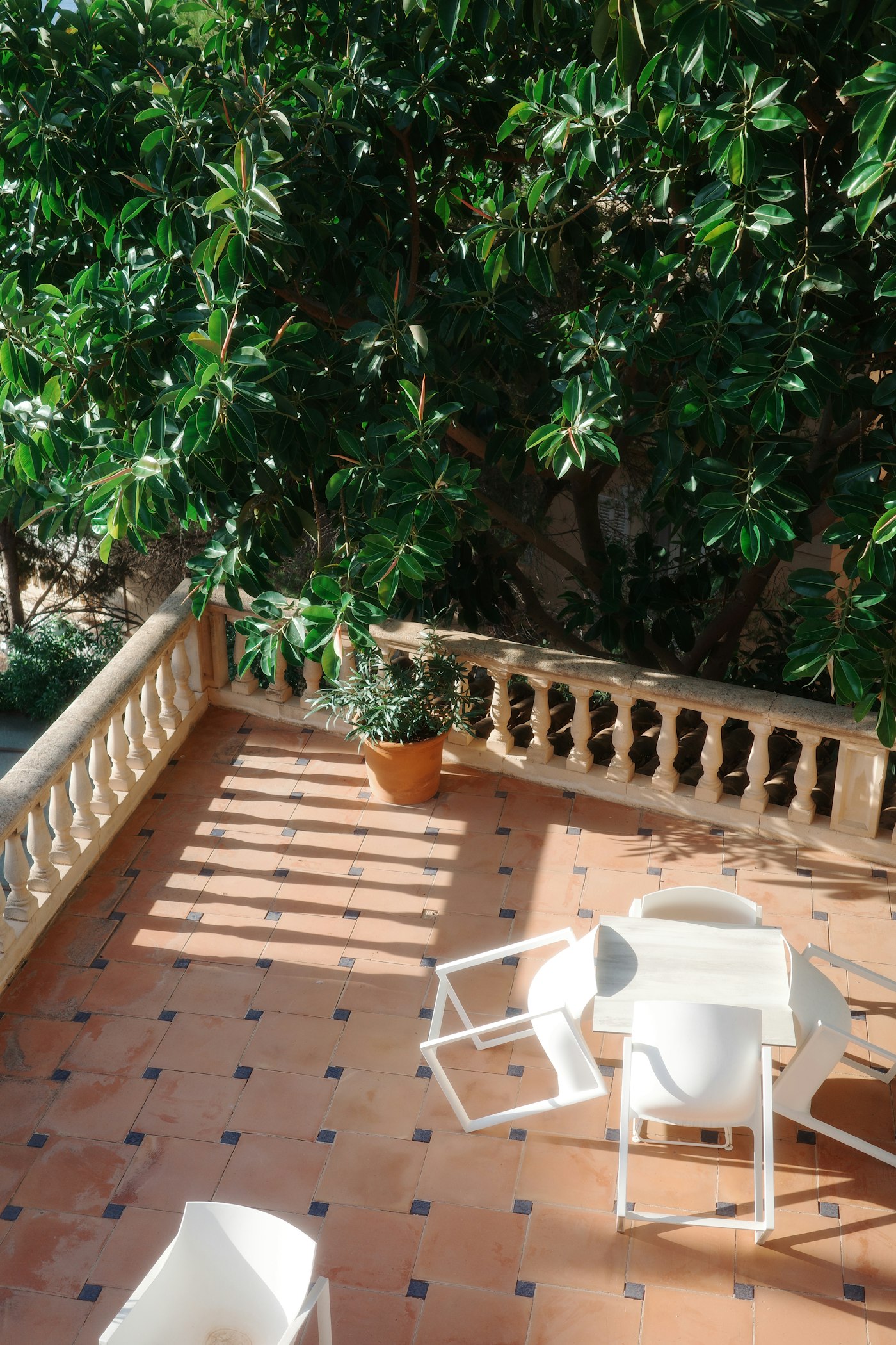 Tiled outdoor terrace with seating and a potted plant